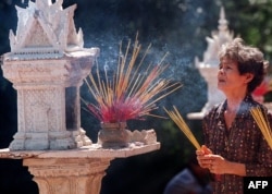 A Cambodian woman burns incense as she prays for good fortune and health in front of a small prayer house at Wat Phnom Pagoda, Phnom Penh, Jan. 31, 1999.