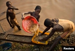FILE - Boys pan for gold on a riverside at Iga Barriere, 25 km (15 miles) from Bunia, in the resource-rich Ituri region of eastern Congo, Feb. 16, 2009.