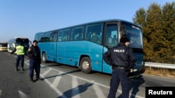 Greek police officers direct buses carrying hundreds of migrants, who were stranded on the Greek-Macedonian border and blocked rail traffic, after a police operation near the village of Idomeni, Greece, Dec. 9, 2015. 