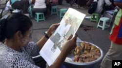 A Myanmar snack vendor reads a weekly journal as she waits for customers on Monday, Nov. 8, 2010, in Yangon, Myanmar. (AP Photo/Khin Maung Win)
