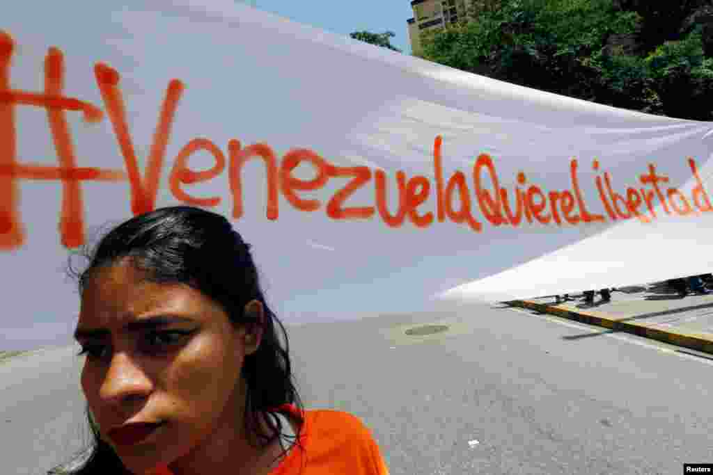 An opposition supporter stands next to a banner during a protest to demand the opening of international humanitarian aid meant to bring medicine and food into the country, in Caracas, Venezuela. The banner reads "Venezuela wants freedom."
