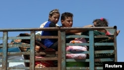 Children ride on a truck with belongings in Deraa countryside, Syria, June 22, 2018.