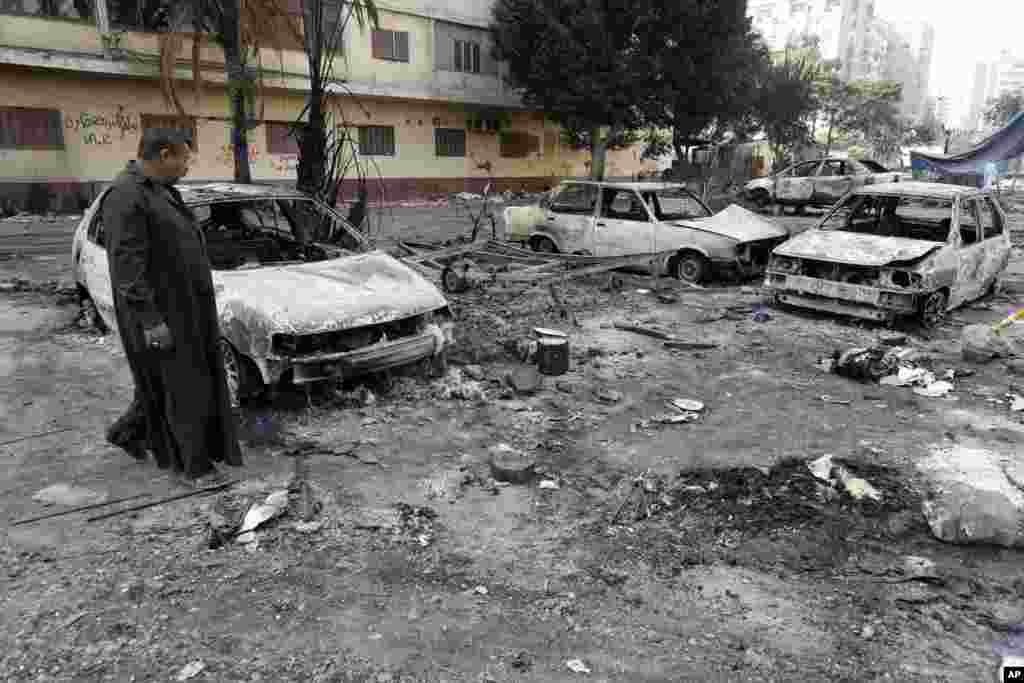 A man walks through debris from what is left of burned vehicles outside the Rabaah al-Adawiya mosque, Cairo, August 16, 2013. 