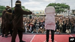 Shariah law official whips one of two men convicted of gay sex during a public caning outside a mosque in Banda Aceh, Aceh province, Indonesia, May 23, 2017. 