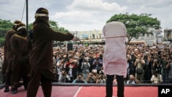 Petugas mencambuk satu dari dua pria yang dihukum di depan umum karena melakukan hubungan seks sesama jenis, di luar sebuah masjid di Banda Aceh, provinsi Aceh, Indonesia, 23 Mei 2017. (AP Photo/Heri Juanda)