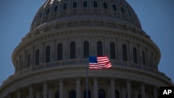 FILE - An American flag flies in front of the dome of the United States Capitol building, July 26, 2011.