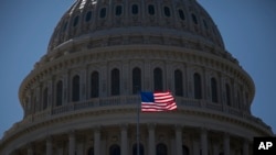 FILE - An American flag flies in front of the dome of the United States Capitol building, July 26, 2011.