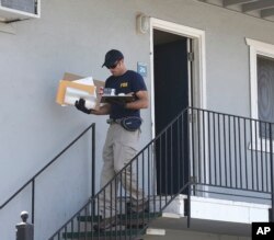 A federal agent removes items from an apartment following the arrest of a 45-year-old Iraqi refugee, Omar Ameen, Wednesday, Aug. 15, 2018, in Sacramento, Calif.