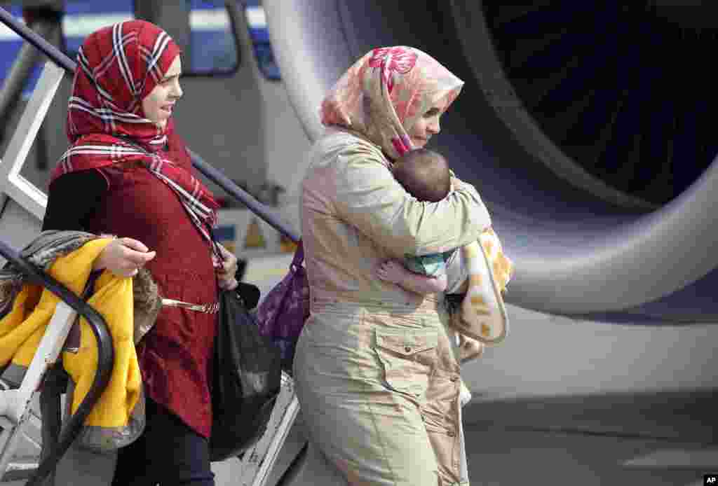 Members of a group of refugees from Syria leave an airplane at the airport in Hannover, Germany, Sept. 11, 2013.
