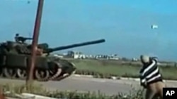 A man throws a rock at a passing tank in a location given as Deraa on April 25, 2011, in this still image from an amateur video