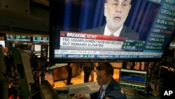 The news conference of Federal Reserve Chairman Ben Bernanke appears on a television screen at a trading post on the floor of the New York Stock Exchange, Dec. 18, 2013.