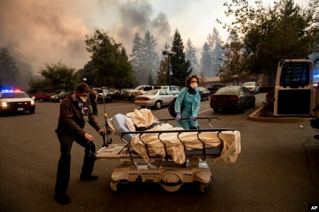Medical personnel evacuate patients as the Feather River Hospital burns while the Camp Fire rages through Paradise, Calif., Nov. 8, 2018.