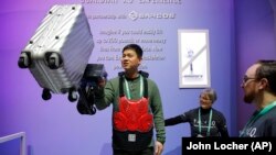 Eric Lynn lifts a 50 pound suitcase with the help of a powered arm similar to the Sarcos Robotics Guardian XO at the Delta Airlines booth during the CES tech show, Wednesday, Jan. 8, 2020, in Las Vegas.