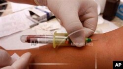 FILE - A health worker takes a blood sample for an HIV test in San Salvador.