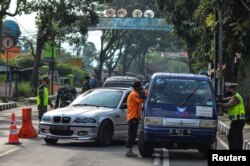 Petugas memeriksa mobil di pos pemeriksaan di Tasikmalaya, Provinsi Jawa Barat, pada hari pertama larangan mudik menjelang lebaran di tengah pandemi COVID-19, 6 Mei 2021. (Antara Foto / Adeng Bustomi / via Reuters.)