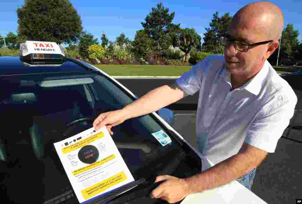 Chauffeur de taxi français, Gérard Gomez, colle une affiche portant la mention "Stop Uber" sur son parebrise lors d'un blocus des chauffeurs de taxi à l'aéroport de Biarritz, à l’ouest de la France, le 25 Juin, 2015. 