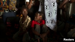 FILE - Children sit inside a container truck as they wait to depart to the west of the country towards the border with Cameroon, in a convoy escorted by African Union (AU) peacekeeping forces as they flee sectarian violence in the capital Bangu.