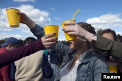 FILE - Revelers hold up yellow plastic cups during party in New Jersey, Oct. 17, 2015.