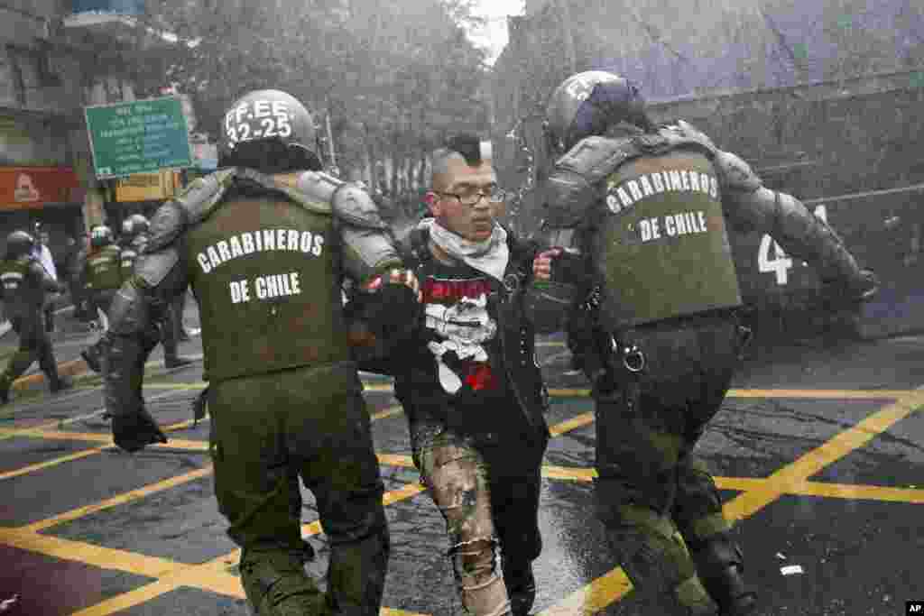 智利圣地亚哥，一位学生在参加抗议游行时对警察扔石头，被警方抓走。学生要求政府整顿教育经费制度，包括取消学生贷款上学所欠债务。（2017年5月9日）