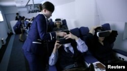 Seorang staf berpakaian pramugari membantu para pengunjung mengenakan kacamata realitas maya di "First Airlines", fasilitas kelas satu penerbangan virtual di Tokyo, Jepang, 14 Februari 2018.