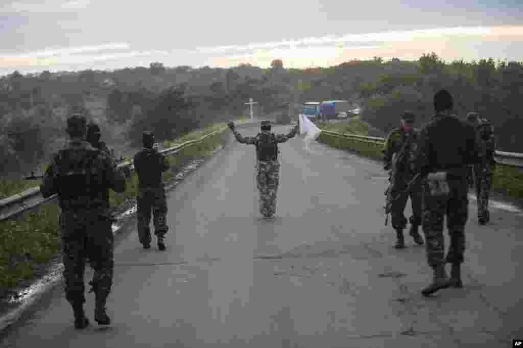 Pro-Russian fighters wave a white flag to start a handover of the bodies of Ukrainian troops killed in a plane shot down near Luhansk, at a check point in the village of Karlivka near Donetsk, eastern Ukraine, June 18, 2014.