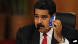 El presidente Nicolás Maduro muestra una copia miniatura de la Constitución, durante la reunión de diálogo con la oposición.