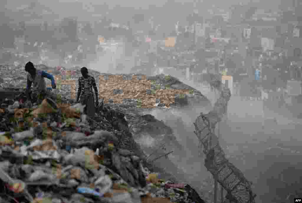 Ragpickers collect usable material as smoke rises from a garbage dump at the Bhalswa landfill site in New Delhi, India.