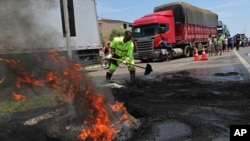 A fireman works to extinguish a burning tire barricade set on fire by protesting truckers, in Brasilia, Brazil, Nov. 9, 2015. 