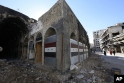 FILE - Damaged shops are seen with new doors in the old city of Homs, Syria on Tuesday, Dec. 8, 2015.