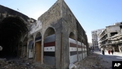 FILE - Damaged shops are seen with new doors in the old city of Homs, Syria, Dec. 8, 2015.