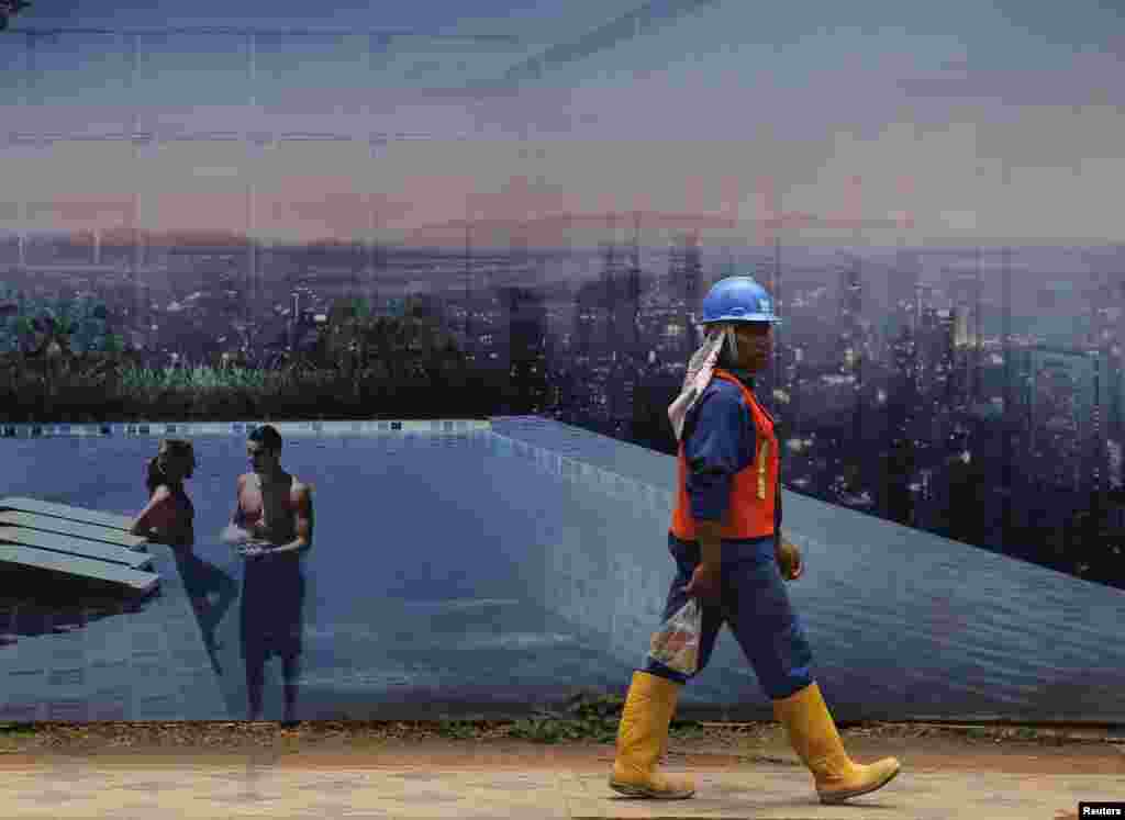 An Indonesian worker carries his lunch as he walks past an advertisement of an apartment at Sudirman Business District in Jakarta.