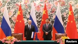 Russia's President Vladimir Putin (L) and his Chinese counterpart Xi Jinping stand during a signing ceremony at the Diaoyutai State Guesthouse in Beijing, Nov. 9, 2014. 