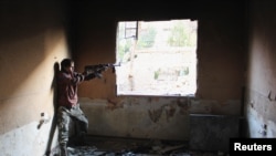 Mohammad, a 13 year-old fighter from the Free Syrian Army, aims his weapon as he takes cover inside a room in Aleppo's Bustan al-Basha district, Oct. 28, 2013.