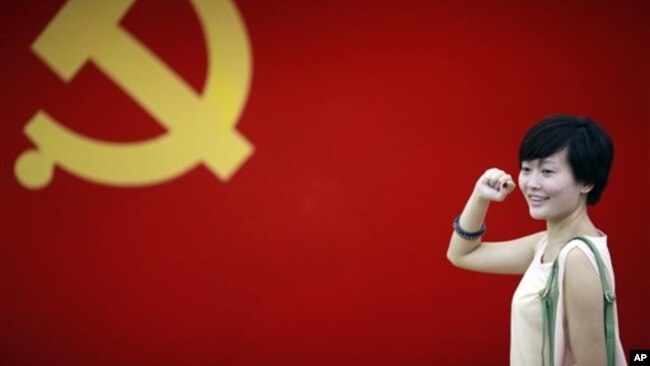 在上海的中共第一次代表大会会址,一名女子在中国共产党党旗下摆出宣誓姿势 (2012年7月1日)