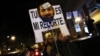 A demonstrator carries a sign with a mask resembling Spanish Prime Minister Mariano Rajoy, as they cut off traffic after a protest outside the headquarters of the ruling People's Party (Partido Popular) in Madrid, February 2, 2013.