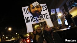 A demonstrator carries a sign with a mask resembling Spanish Prime Minister Mariano Rajoy, as they cut off traffic after a protest outside the headquarters of the ruling People's Party (Partido Popular) in Madrid, February 2, 2013.