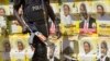 FILE - A Ugandan policeman is seen on patrol against the backdrop of numerous campaign posters for long-time President Yoweri Museveni, on a street in Kampala, Uganda, Feb. 17, 2016.