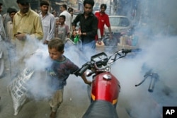 A boy tries to outrun a man fumigating for mosquitoes in an effort to combat dengue fever, on the streets of Lahore, Pakistan, Sept. 20, 2011.