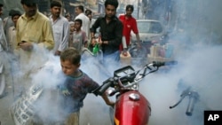 A boy tries to outrun a man fumigating for mosquitoes in an effort to combat dengue fever, on the streets of Lahore, Pakistan, September 20, 2011.