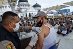 Seorang pria disuntik vaksin COVID-19 Sinovac di depan Masjid Agung Baiturrahman, Banda Aceh, 30 Maret 2021. (Foto: CHAIDEER MAHYUDDIN / AFP)