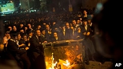 Ultra-orthodox Jews push a burning garbage bin towards Israeli security forces during a protest against military conscription of yeshiva students, in Jerusalem, May 16, 2013. 