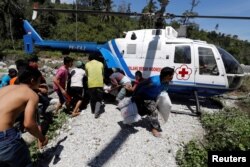 Villagers affected by the earthquake rush an Indonesian Red Cross helicopter carrying aid in Biromaru, Sigi Regency, south of Palu, Central Sulawesi, Indonesia, Oct. 5, 2018.