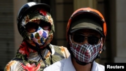 People wear protective masks while riding on a street in Hanoi, Vietnam, May 21, 2018. 
