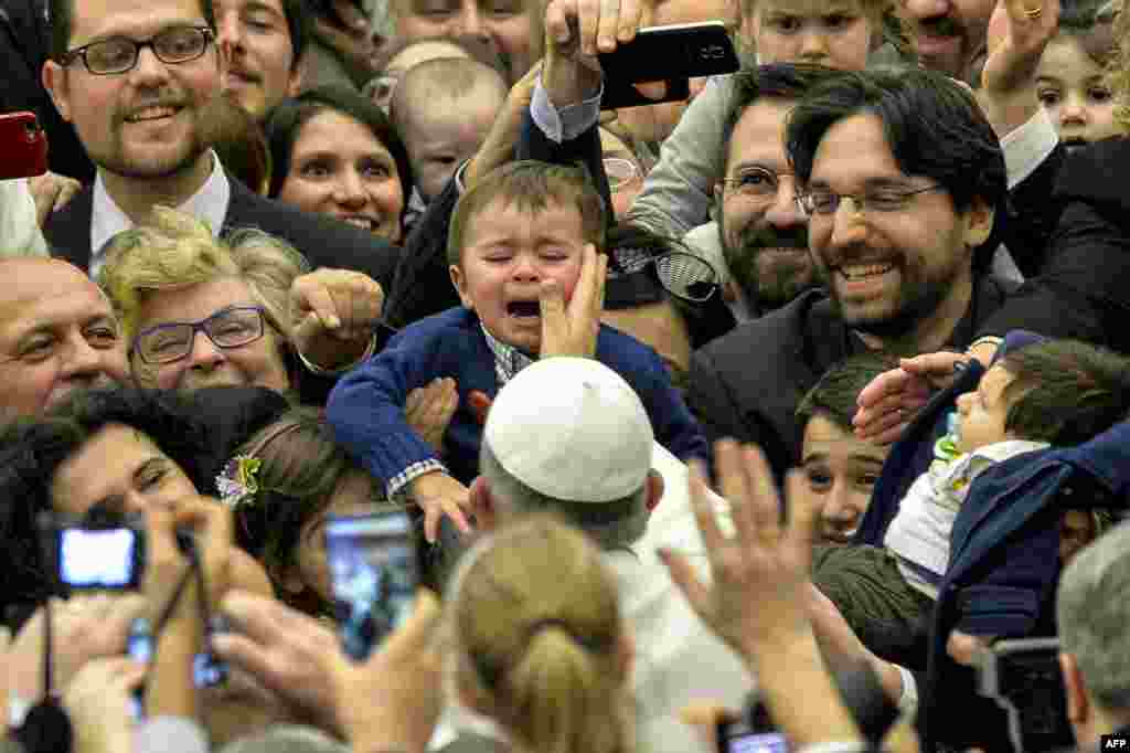 Pope Francis strokes a crying child&#39;s face as he arrives for a meeting in Aula Paolo VI at the Vatican.