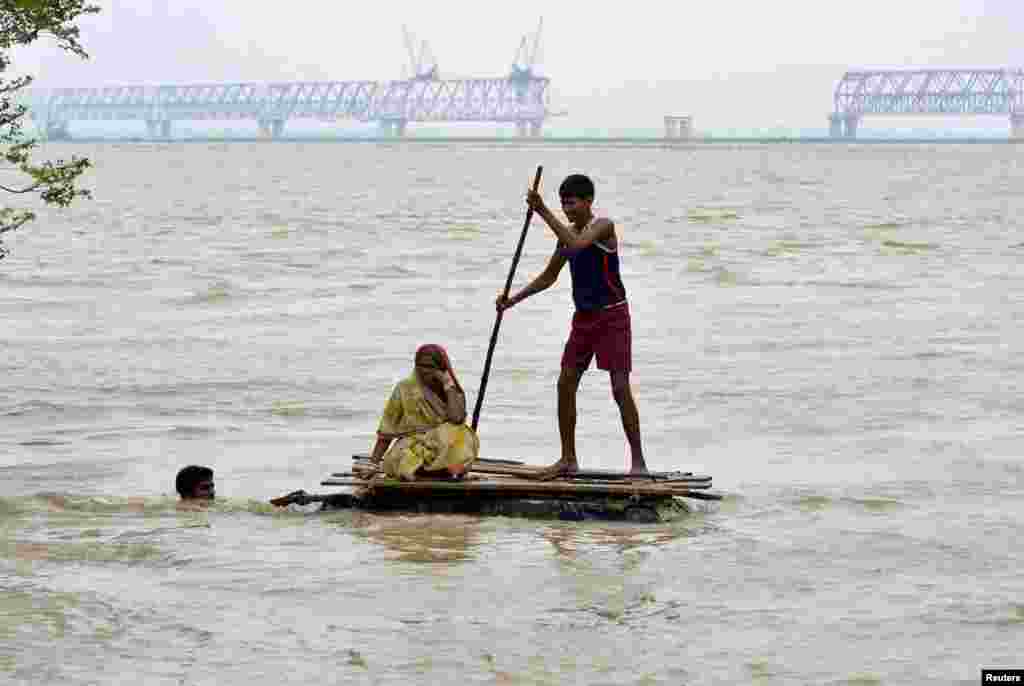 Flood-affected villagers use a temporary raft as they navigate through the floodwaters of River Ganges to move to safer grounds, after heavy rains at Patna district in the eastern Indian state of Bihar.