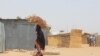 Une femme porte du bois sur la tête du camp informel de Yawuri à la périphérie de Maiduguri, capitale de l'État de Borno, le 29 mars 2021.