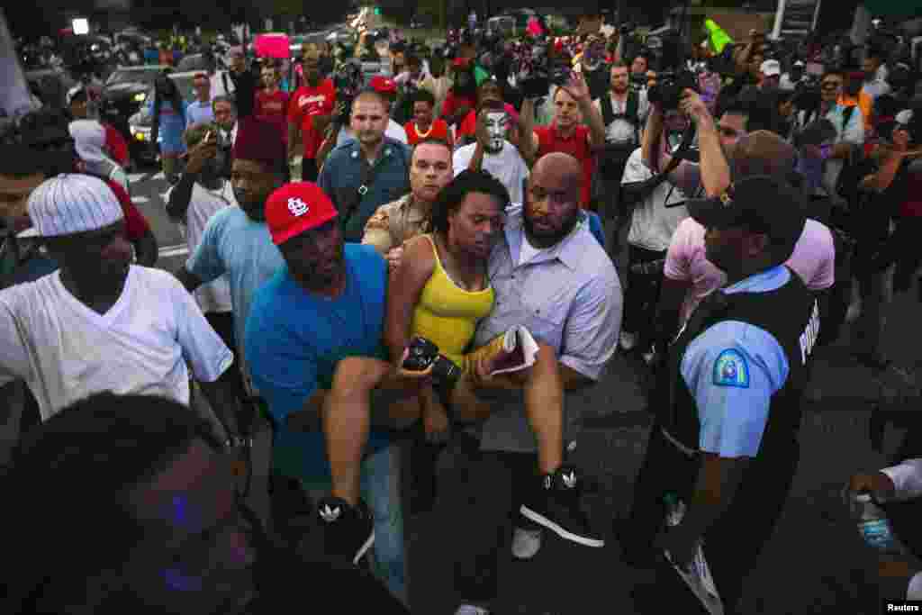 Men carry a woman in need of medical assistance during a peaceful demonstration in Ferguson, Missouri, Aug. 14, 2014.