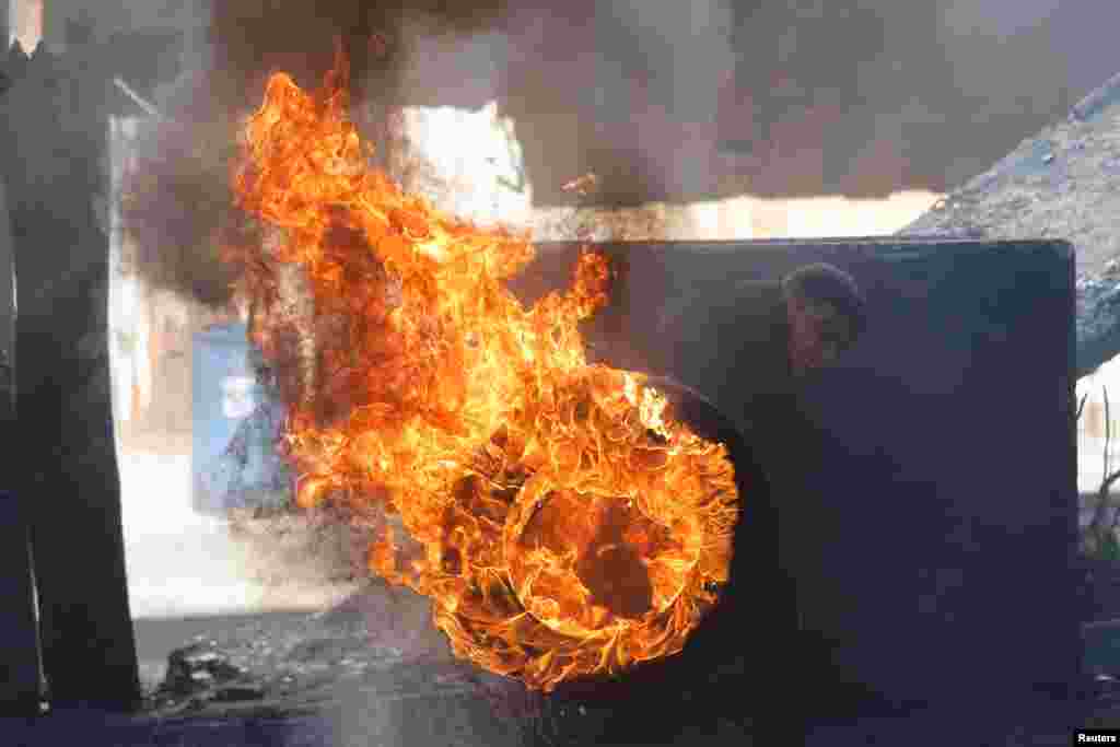 A Palestinian pushes a burning tire during clashes in Hebron, in the Israeli-occupied West Bank.