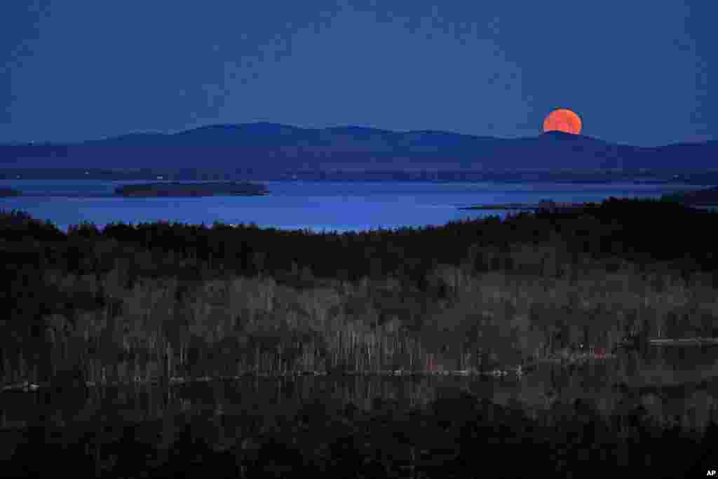 The nearly-full moon sets at dawn behind the Camden Hills in this view looking west across Penobscot Bay, near Camden, Maine.