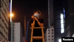 A student at a command post climbs on a ladder while watching for any aggressive moves by riot police at Mongkok shopping district in Hong Kong October 5, 2014. 